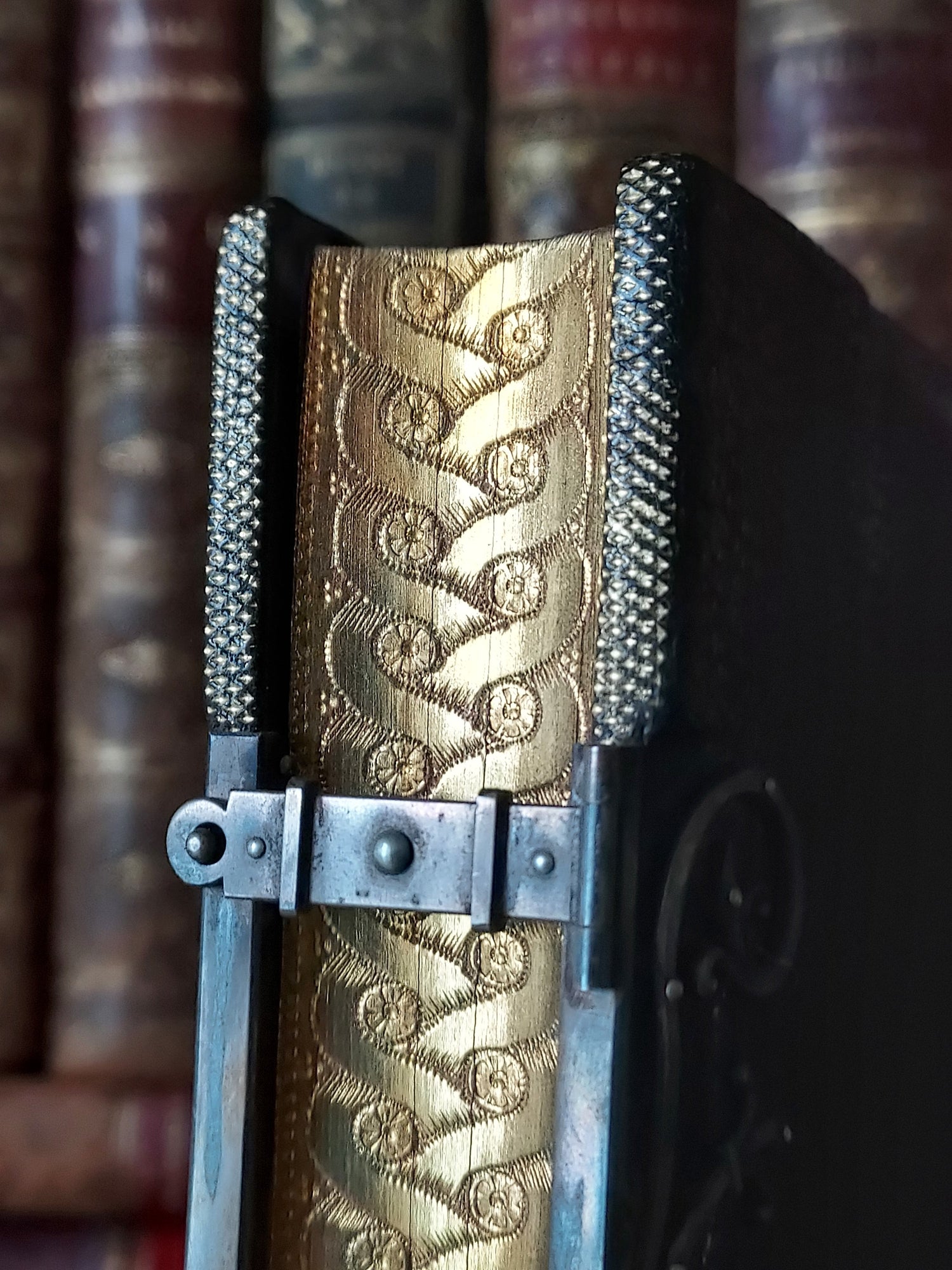 Antique books on a shelf with page edges decorated with patterns known as gauffering. 